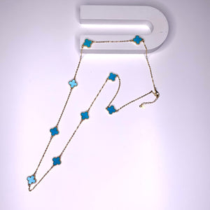Long necklace with aqua blue four-leaf clover stations on a gold paper chain