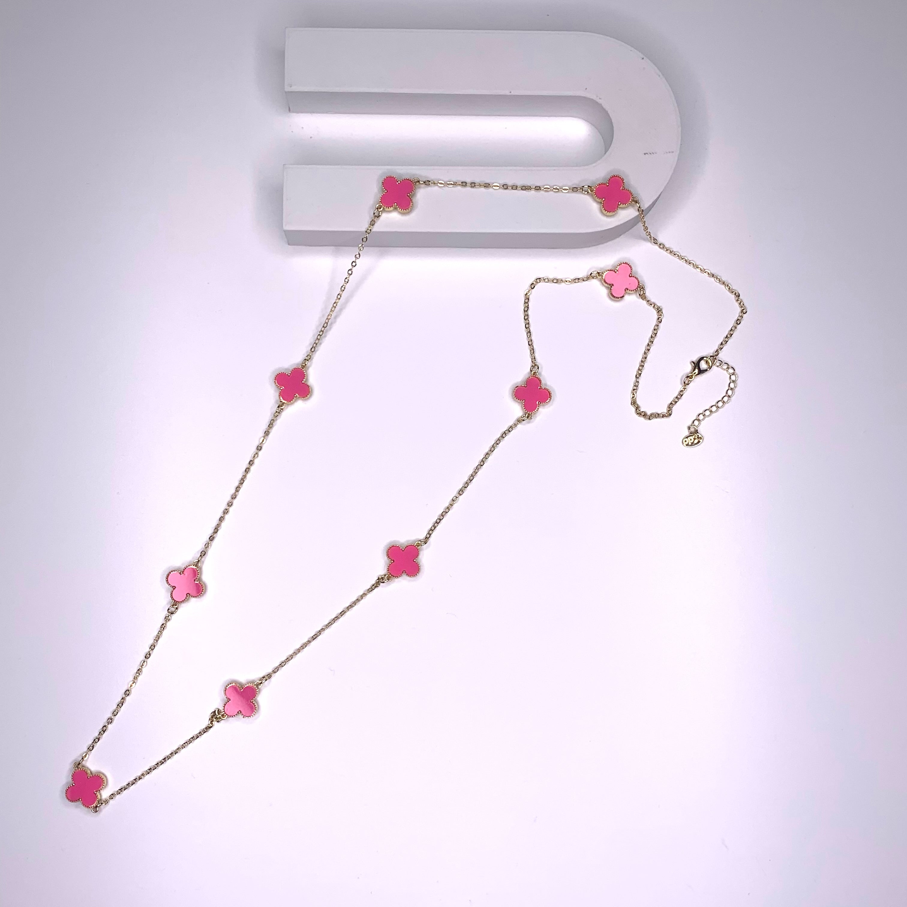 Long necklace with hot pink four-leaf clover stations on a gold paper chain