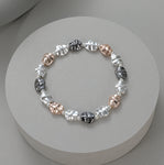Elasticated bracelet with matte silver, shiny silver, rose and pewter battered circular stations