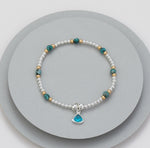 Elasticated bracelet with silver beads, gold beads and meridian green beads - with an aqua charm