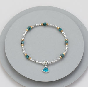Elasticated bracelet with silver beads, gold beads and meridian green beads - with an aqua charm