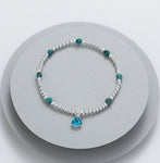 Elasticated bracelet with silver beads and meridian green beads - with an aqua charm