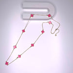 Long necklace with hot pink four-leaf clover stations on a gold paper chain