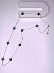 Long necklace with green four-leaf clover stations on a gold paper chain